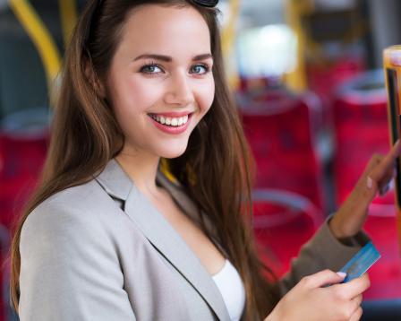A smiling woman uses a card machine.